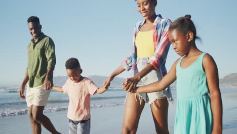 Happy-african-american-couple-walking-with-daughter-and-son-on-sunny-beach