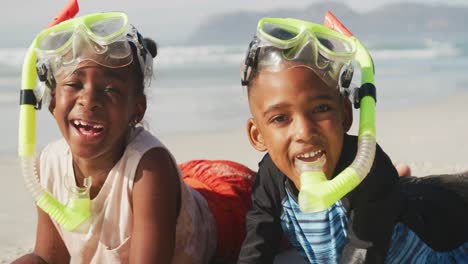 African-american-brother-and-sister-wearing-scuba-diving-mask-with-a-snorkel-at-the-beach