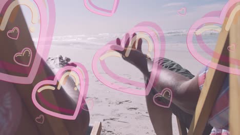 Animation-of-hearts-over-senior-african-american-couple-lying-on-sunbeds-on-sunny-beach