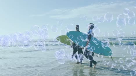 Animation-of-bubbles-over-senior-african-american-couple-with-surfboards-on-sunny-beach