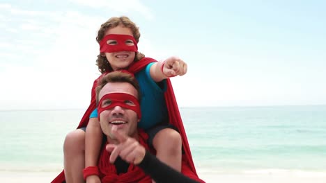 Animation-of-do-it-for-them-over-happy-caucasian-father-and-son-in-superhero-costumes-on-beach