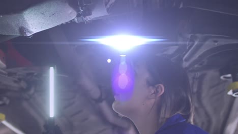 Animation-of-glowing-light-over-caucasian-female-car-mechanic-working-in-workshop