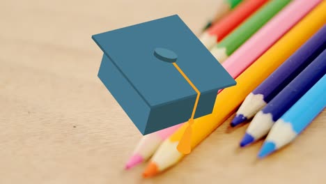 Animation-of-mortarboard-moving-over-coloured-pencils-on-desk