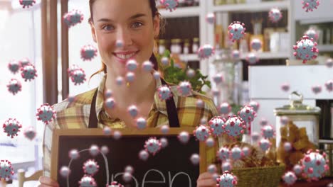 Animation-of-virus-cells-over-happy-caucasian-waitress-with-open-sign