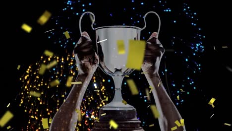 Animation-of-confetti-falling-and-fireworks-over-caucasian-man-holding-silver-cup