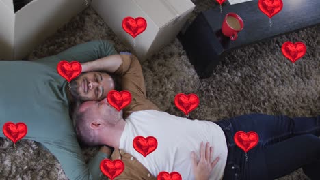 Animation-of-heart-icons-over-diverse-gay-couple-lying