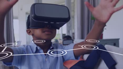 Animation-Eines-Netzwerks-Von-Verbindungen-über-Einem-Glücklichen-Afroamerikanischen-Jungen,-Der-Ein-VR-Headset-Verwendet