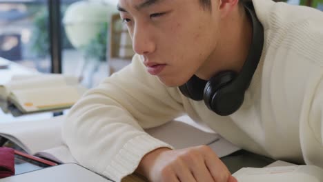 Asiatischer-Männlicher-Teenager-Mit-Kopfhörern,-Der-Im-Wohnzimmer-Schläft-Und-Laptop-Benutzt