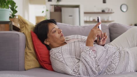 Afroamerikanische-ältere-Frau-Mit-Digitalem-Tablet,-Die-Zu-Hause-Auf-Der-Couch-Liegt