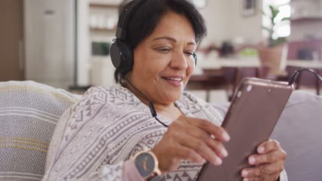 Mujer-Mayor-Afroamericana-Con-Auriculares-Escuchando-Música-En-Una-Tableta-Digital-En-Casa