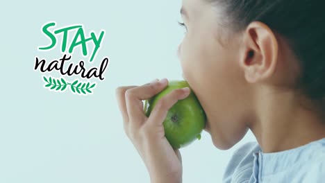 Animation-of-stay-natural-text-over-biracial-girl-eating-green-apple