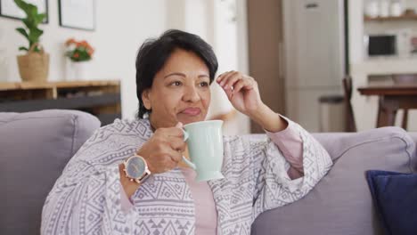 Asiatische-ältere-Frau-Lächelt,-Während-Sie-Zu-Hause-Auf-Der-Couch-Kaffee-Trinkt