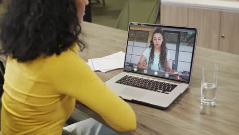 Biracial-businesswoman-using-laptop-for-video-call-with-biracial-business-colleague