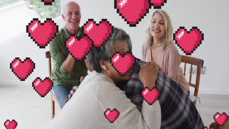 Animation-of-hearts-over-diverse-group-of-seniors-embracing