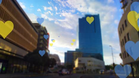 Animation-of-yellow-and-blue-hearts-floating-over-cityscape