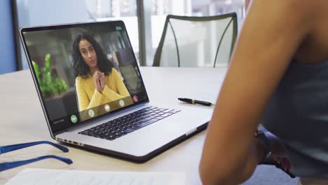 Video-of-biracial-woman-having-video-call-on-laptop-with-biracial-female-coworker