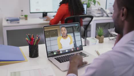 Video-Eines-Afroamerikanischen-Mannes,-Der-Auf-Einem-Laptop-Einen-Videoanruf-Mit-Einer-Gemischtrassigen-Kollegin-Führt