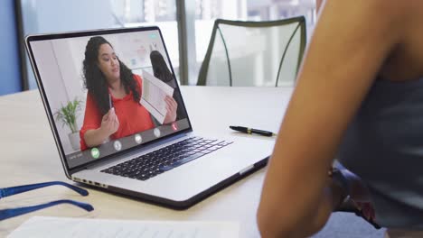 Video-of-biracial-woman-having-video-call-on-laptop-with-biracial-female-coworker