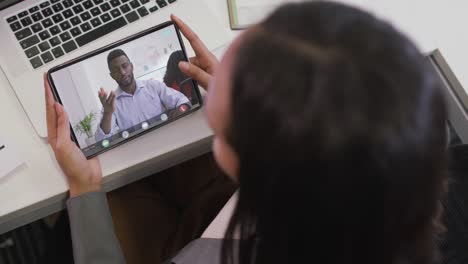 Video-Einer-Gemischtrassigen-Frau,-Die-Auf-Einem-Tablet-Einen-Videoanruf-Mit-Einem-Afroamerikanischen-Männlichen-Kollegen-Führt