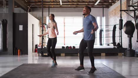 Video-of-fit-diverse-woman-and-man-jumping-on-jumping-rope-at-gym