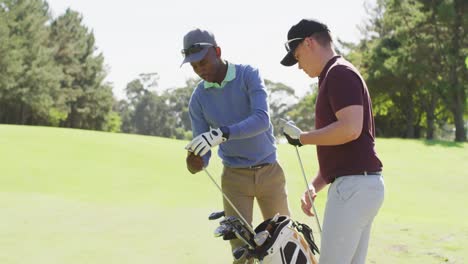 Video-of-diverse-male-friends-preparing-golf-clubs-for-paying-on-golf-field