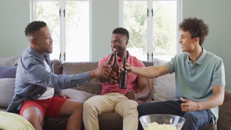 Happy-diverse-male-friends-drinking-beer-and-talking-in-living-room