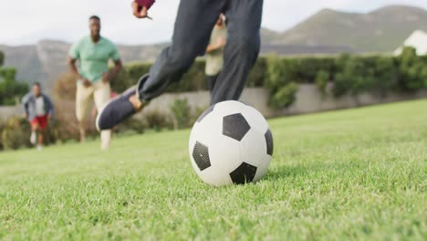 Happy-diverse-male-friends-playing-football-in-garden-on-sunny-day