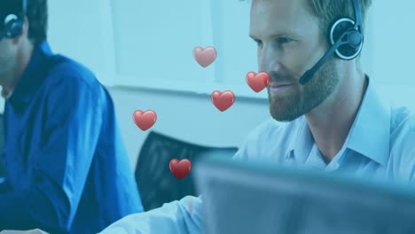 Animation-of-hearts-floating-over-happy-caucasian-male-consultant-at-work