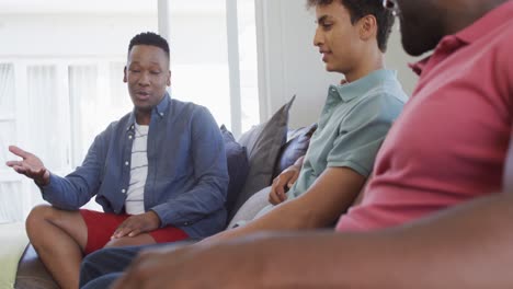 Happy-diverse-male-friends-sitting-and-talking-in-living-room