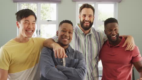 Portrait-of-happy-diverse-male-friends-embracing-in-living-room