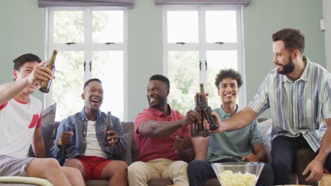 Happy-diverse-male-friends-talking-and-drinking-beer-in-living-room