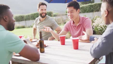 Happy-diverse-male-friends-sitting-at-table-laughing,-eating-and-drinking