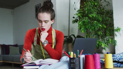 Caucasian-tnon-binary-transgender-woman-working-at-home,-taking-notes