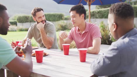 Happy-diverse-male-friends-sitting-at-table-laughing,-eating-and-drinking