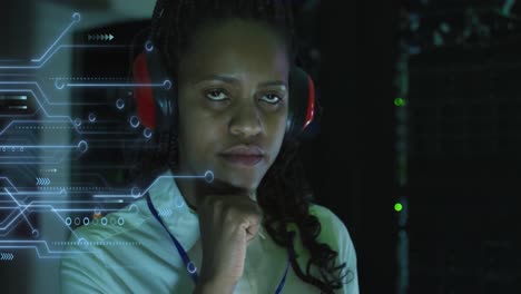 Animation-of-integrated-circuit-over-african-american-woman-working-on-laptop-in-server-room