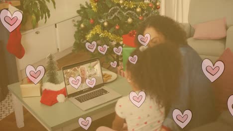 Animation-of-hearts-over-biracial-mother-and-daughter-having-video-call