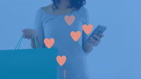 Animation-of-hearts-floating-over-happy-biracial-woman-using-smartphone