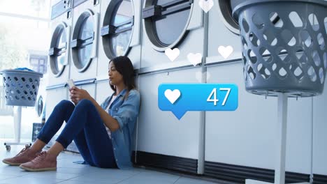 Animation-of-social-media-reactions-over-biracial-woman-in-laundry-room