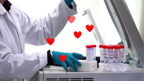 Animation-of-hearts-floating-over-hands-of-caucasian-male-lab-worker-with-samples