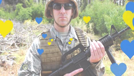 Animation-of-yellow-and-blue-hearts-over-caucasian-male-soldier-with-weapon