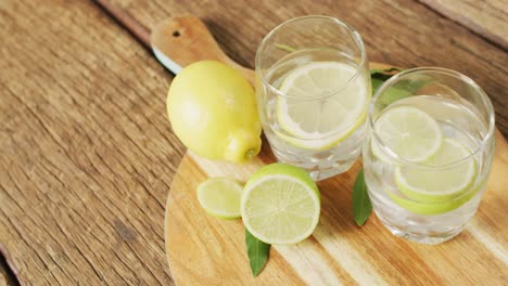 Video-of-glasses-with-lemonade-and-lemons-on-wooden-board-and-wooden-surface