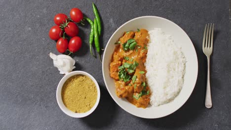 Video-Eines-Tellers-Mit-Reis-Und-Curry,-Soße-Und-Tomaten-Auf-Grauem-Hintergrund