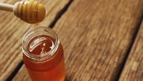 Video-of-honey-in-jar-and-apple-lying-on-wooden-surface