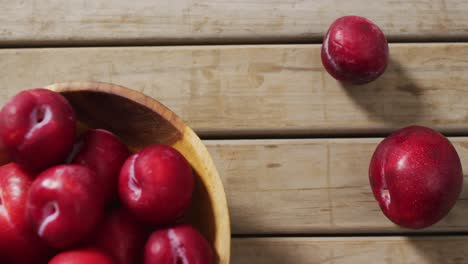 Video-of-fresh-plums-in-bowl-lying-on-wooden-surface
