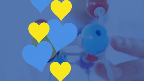 Animation-of-blue-and-yellow-hearts-over-hand-with-3d-chemical-model