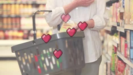 Animation-of-falling-heart-icons-over-senior-caucasian-women-in-the-store
