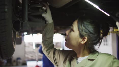 Video-of-biracial-female-car-mechanic-checking-car