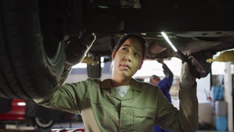 Video-of-biracial-female-car-mechanic-checking-car