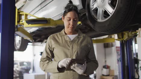 Video-of-biracial-female-car-mechanic-using-tablet-and-looking-at-camera