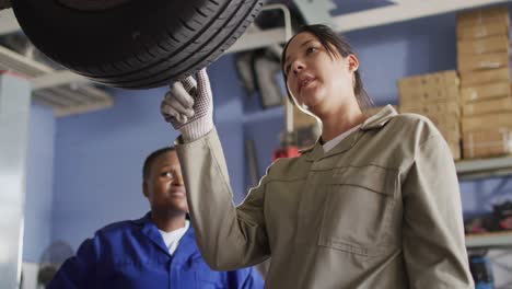 Video-of-two-diverse-female-car-mechanic-talking-and-changing-tyre